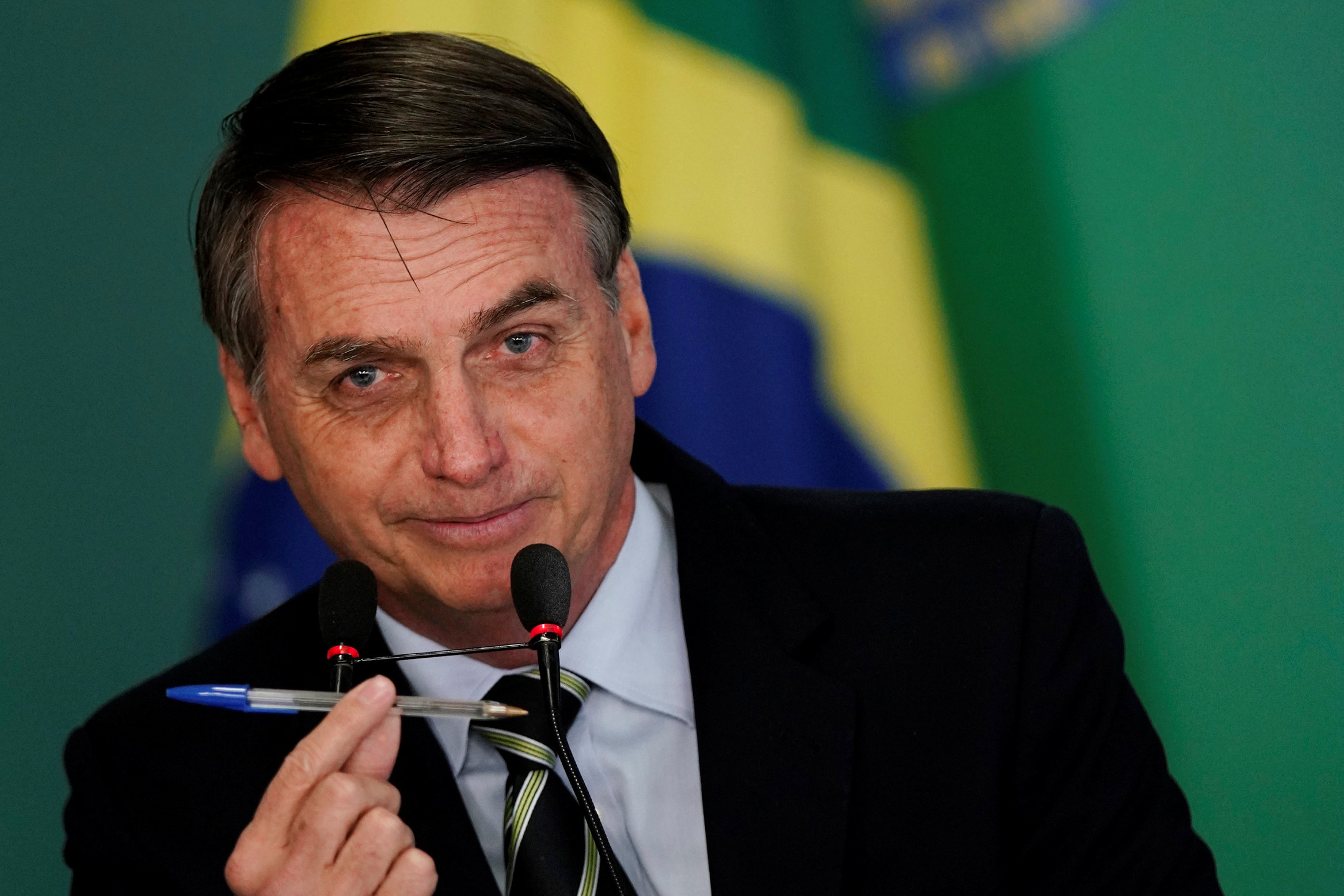 Brazil's President Jair Bolsonaro shows a pen during a signing ceremony of the decree which eases gun restrictions in Brazil, at the Planalto Palace in Brasilia
